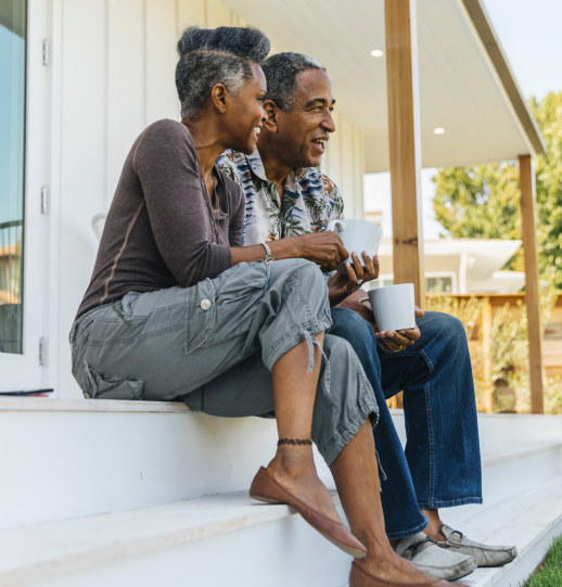 A couple sitting on porch steps drinking coffee